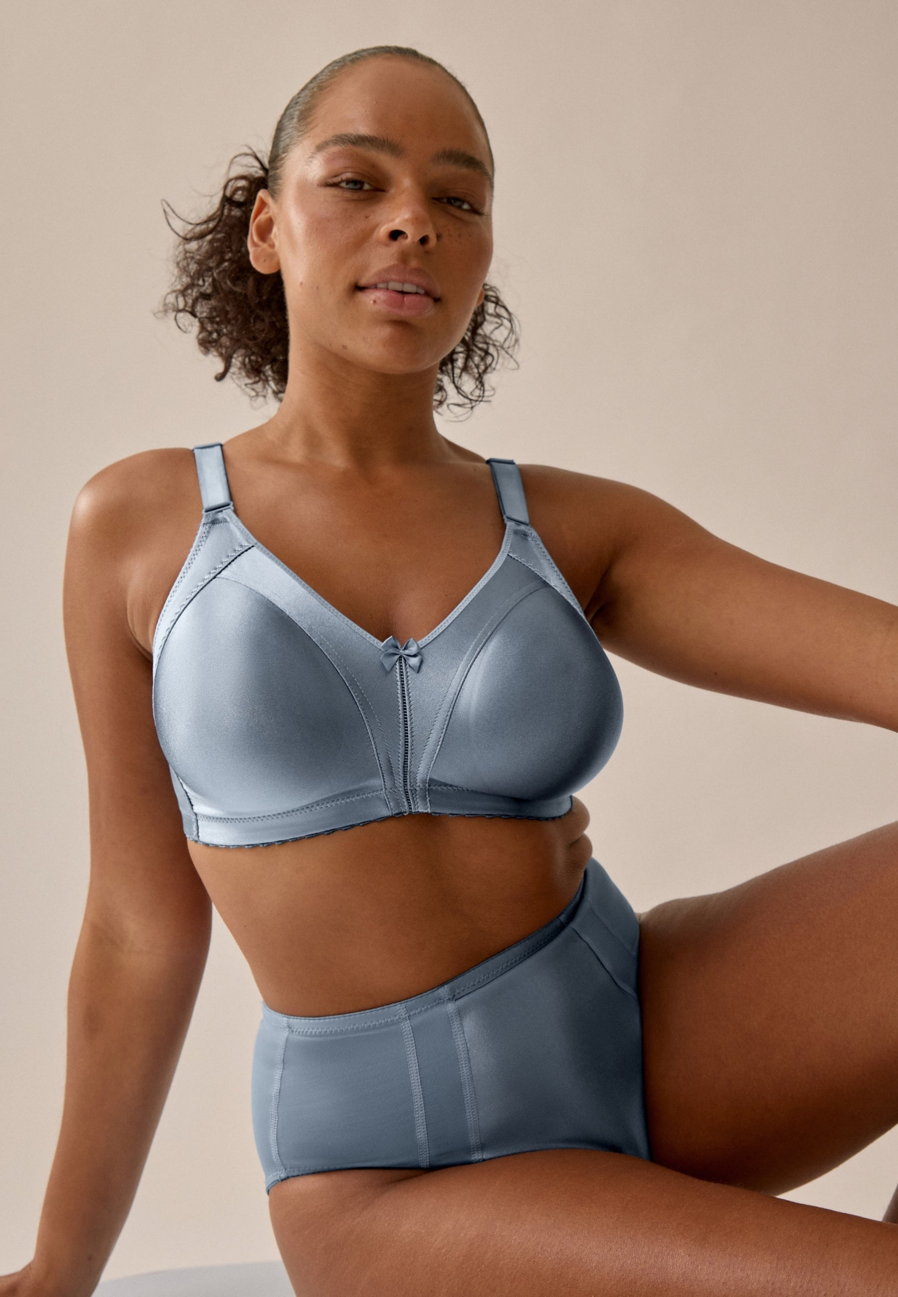 Voorzijde van vrouw die de minimizer bh en minimizer slip met glanzend effect in de kleur moonlight blue van het merk Naturana draagt