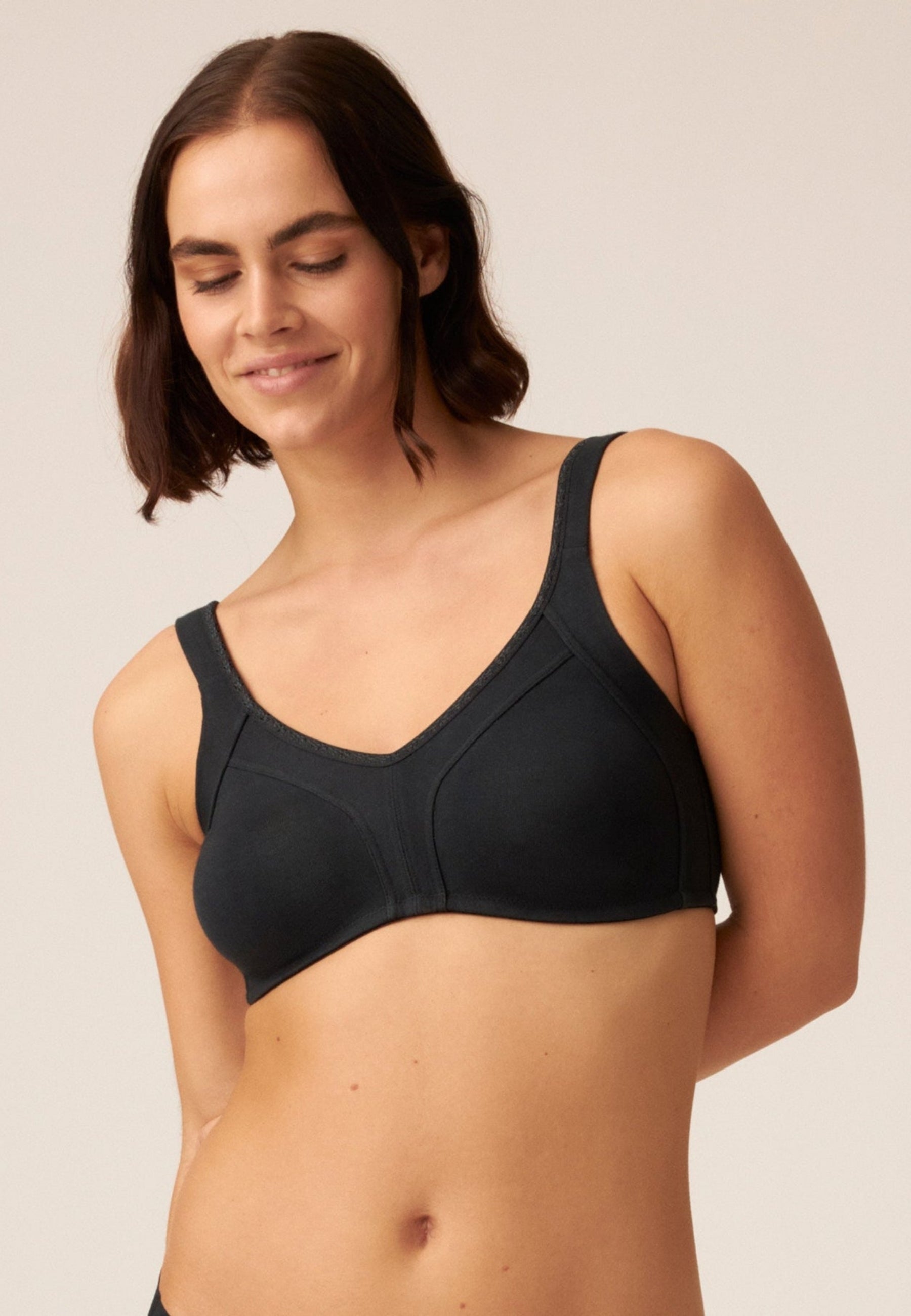 Voorzijde van vrouw die de katoenen minimizer bh met side smoother in de kleur zwart van het merk Naturana draagt