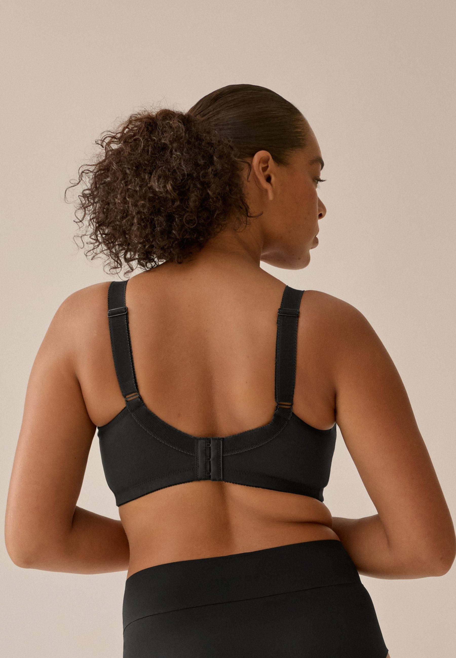 Achterzijde van vrouw die de prothese bh in de kleur zwart van het merk Naturana draagt