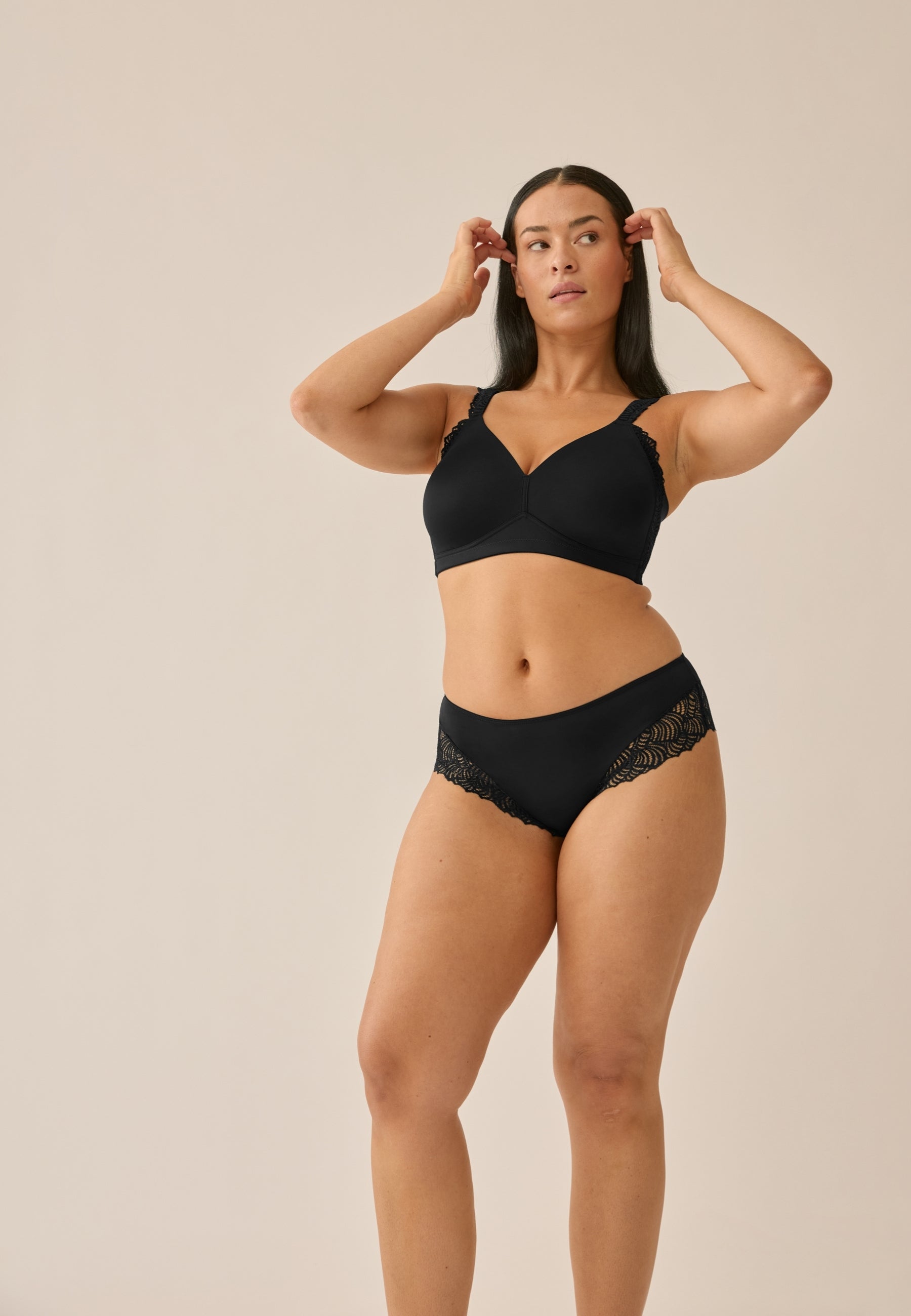 Voorzijde van vrouw die de side smoother bh en hipster met gerecycled kant in de kleur zwart van het merk Naturana draagt