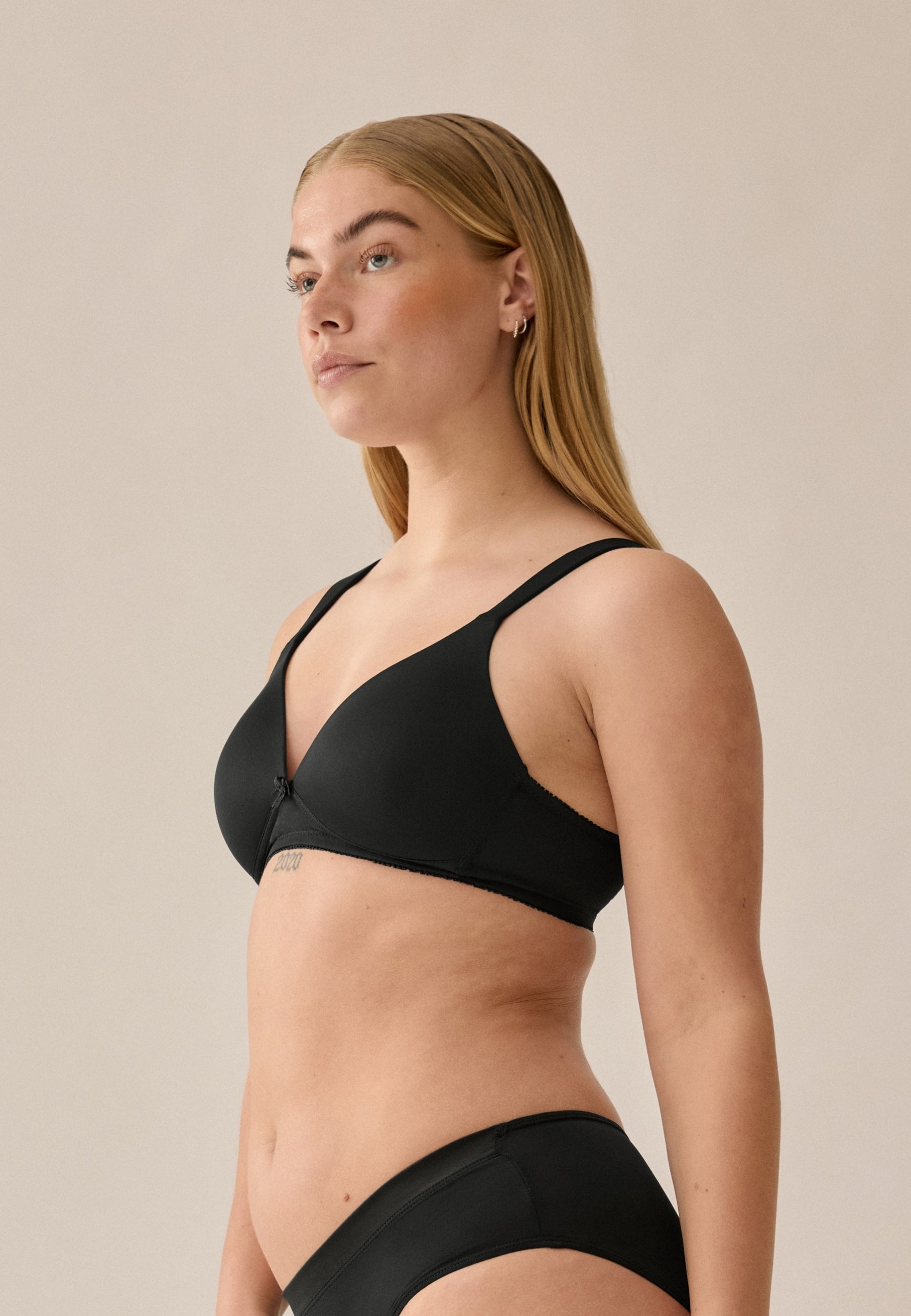 Zijde van vrouw die de soft bh met brede bandjes in de kleur zwart van het merk Naturana draagt