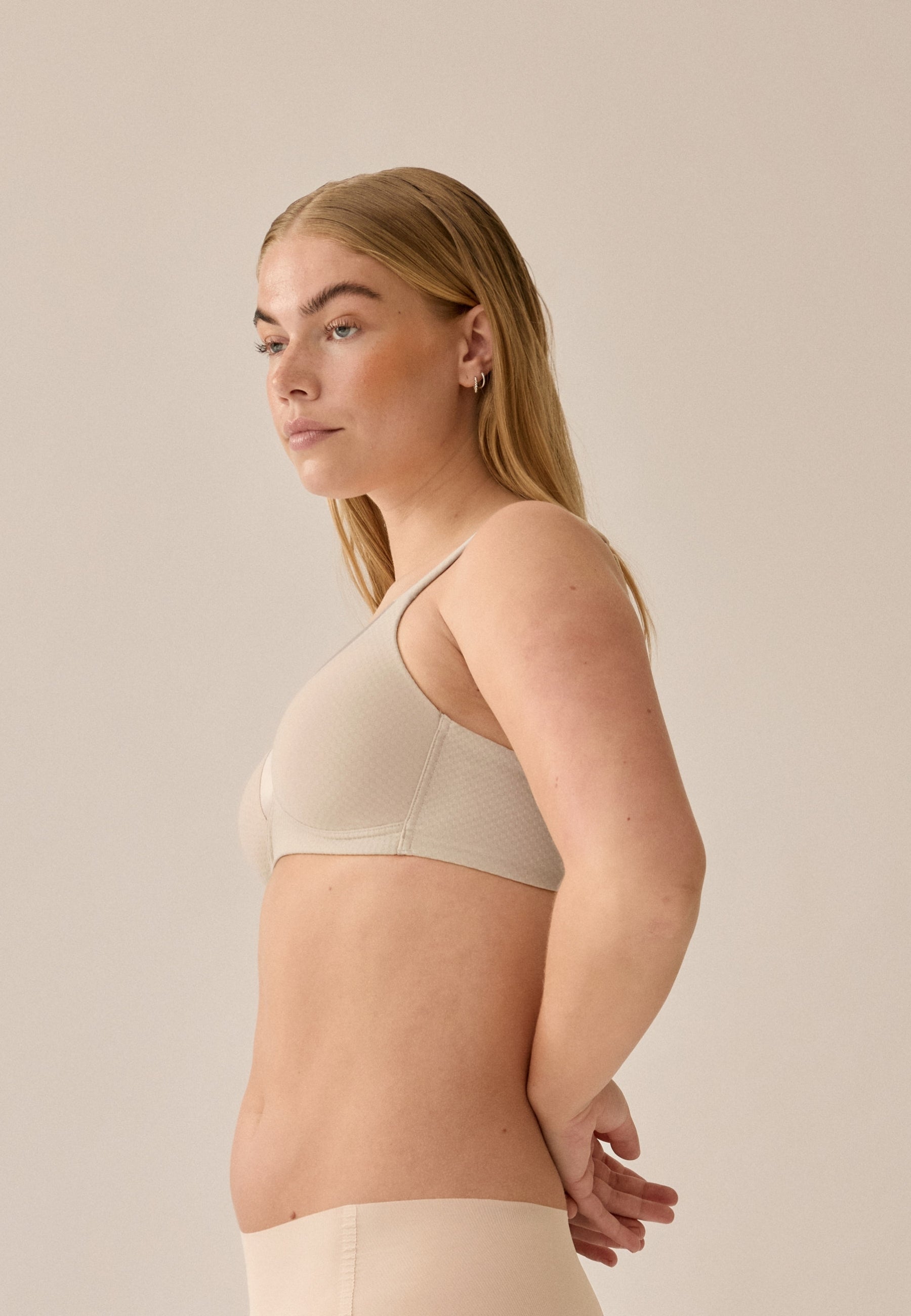 Zijde van vrouw die de soft bh met glansband en patroon in de kleur beige van het merk Naturana draagt