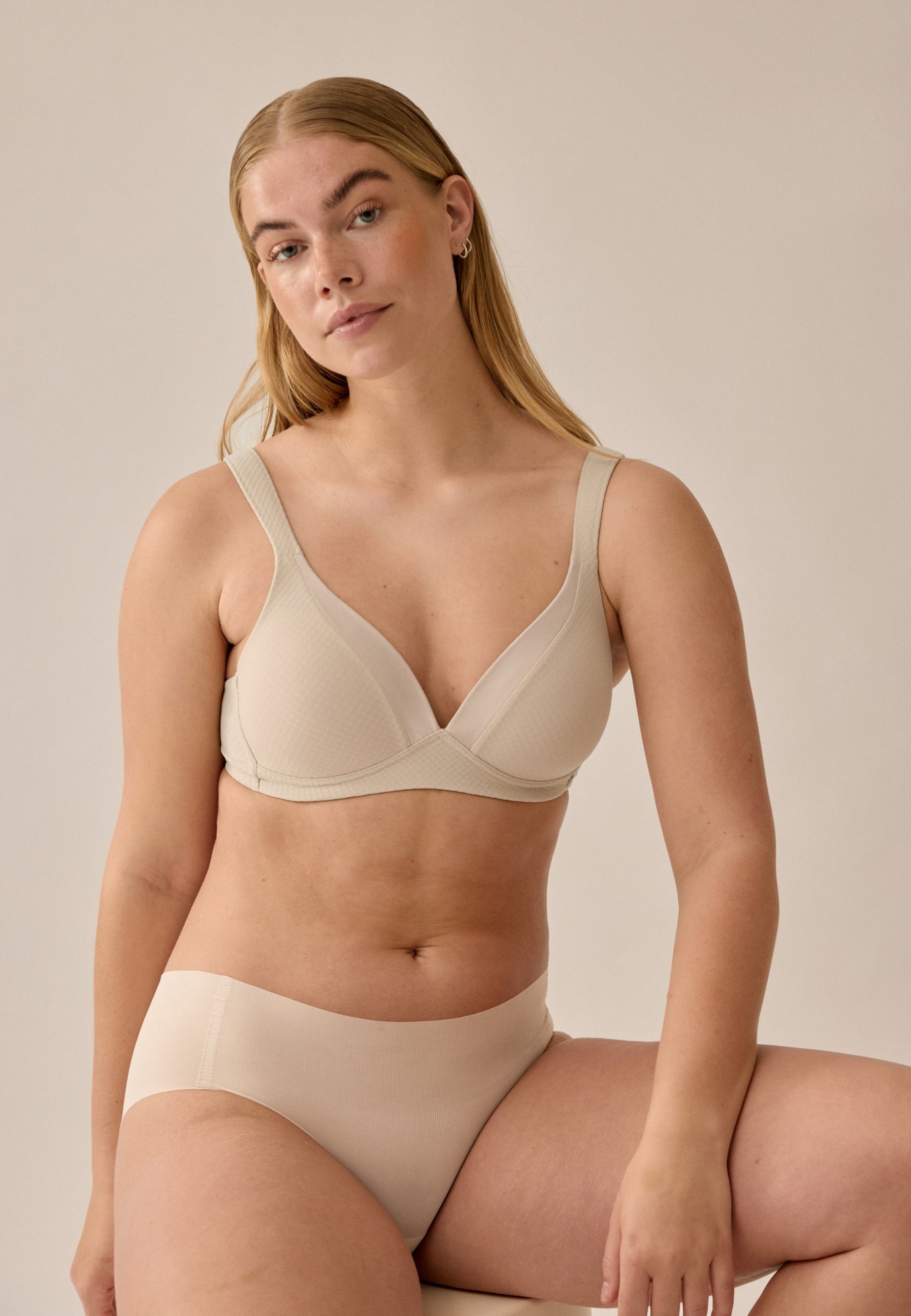 Voorzijde van vrouw die de soft bh met glansband en patroon en de one size slip in de kleur beige van het merk Naturana draagt