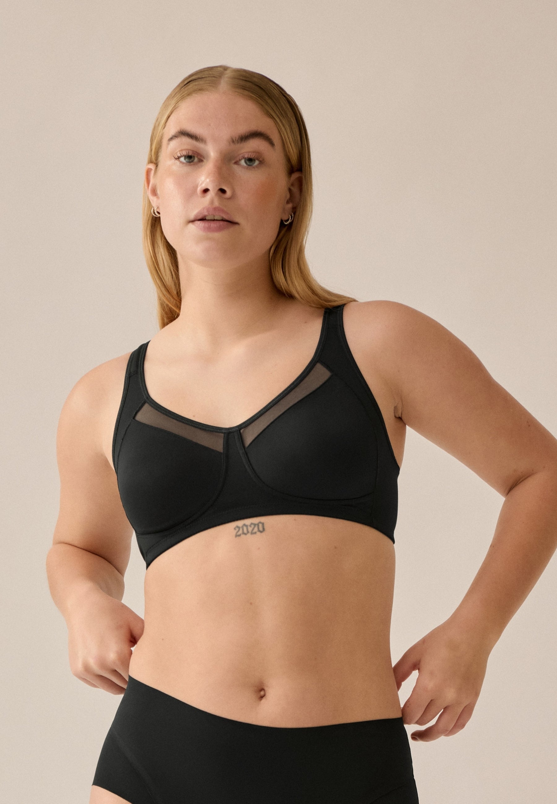 Voorzijde van vrouw die de soft bh met meshrand in de kleur zwart van het merk Naturana draagt