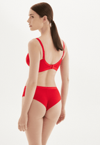 Achterzijde van vrouw die de lambada prothese bh en slip in de kleur rood van het merk Megami draagt