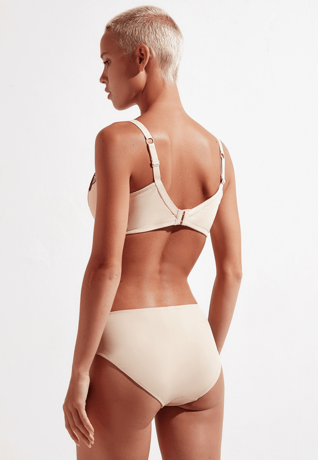 Achterzijde van vrouw die de bloom slip en bloom prothese bh in de kleur beige van het merk Megami draagt