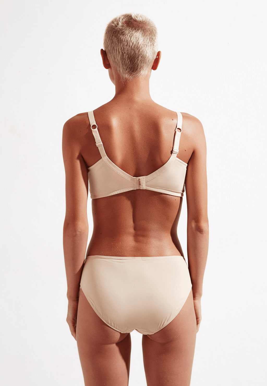 Achterzijde van vrouw die de bloom slip en bloom prothese bh in de kleur beige van het merk Megami draagt