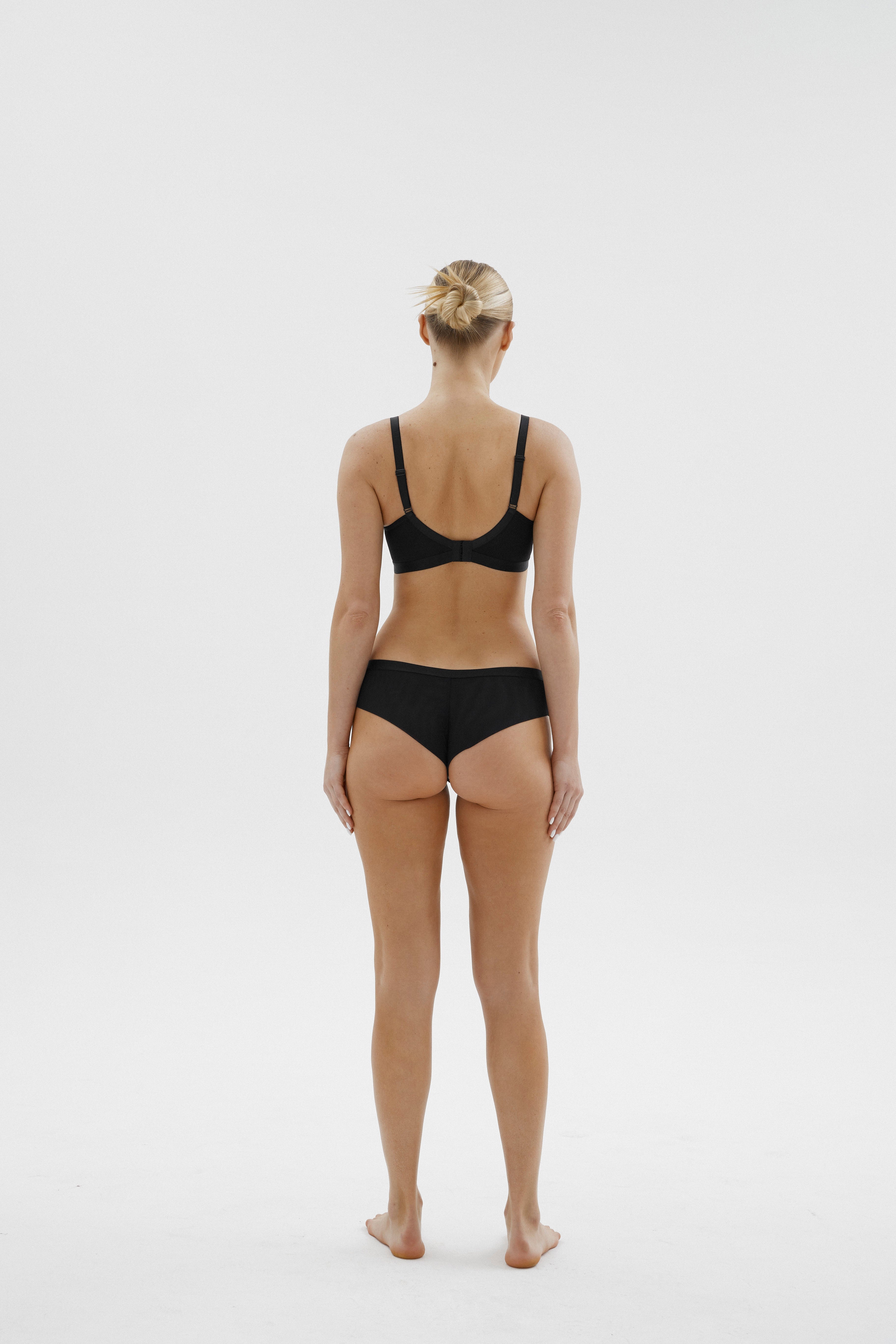 Achterzijde van vrouw die de lambada prothese bh en de lambade slip in de kleur zwart van het merk Megami draagt