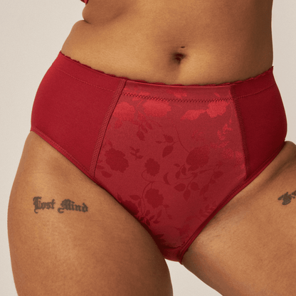 Voorzijde van vrouw die de minimizer slip met bloemenpatroon in de kleur deep claret van het merk Naturana draagt