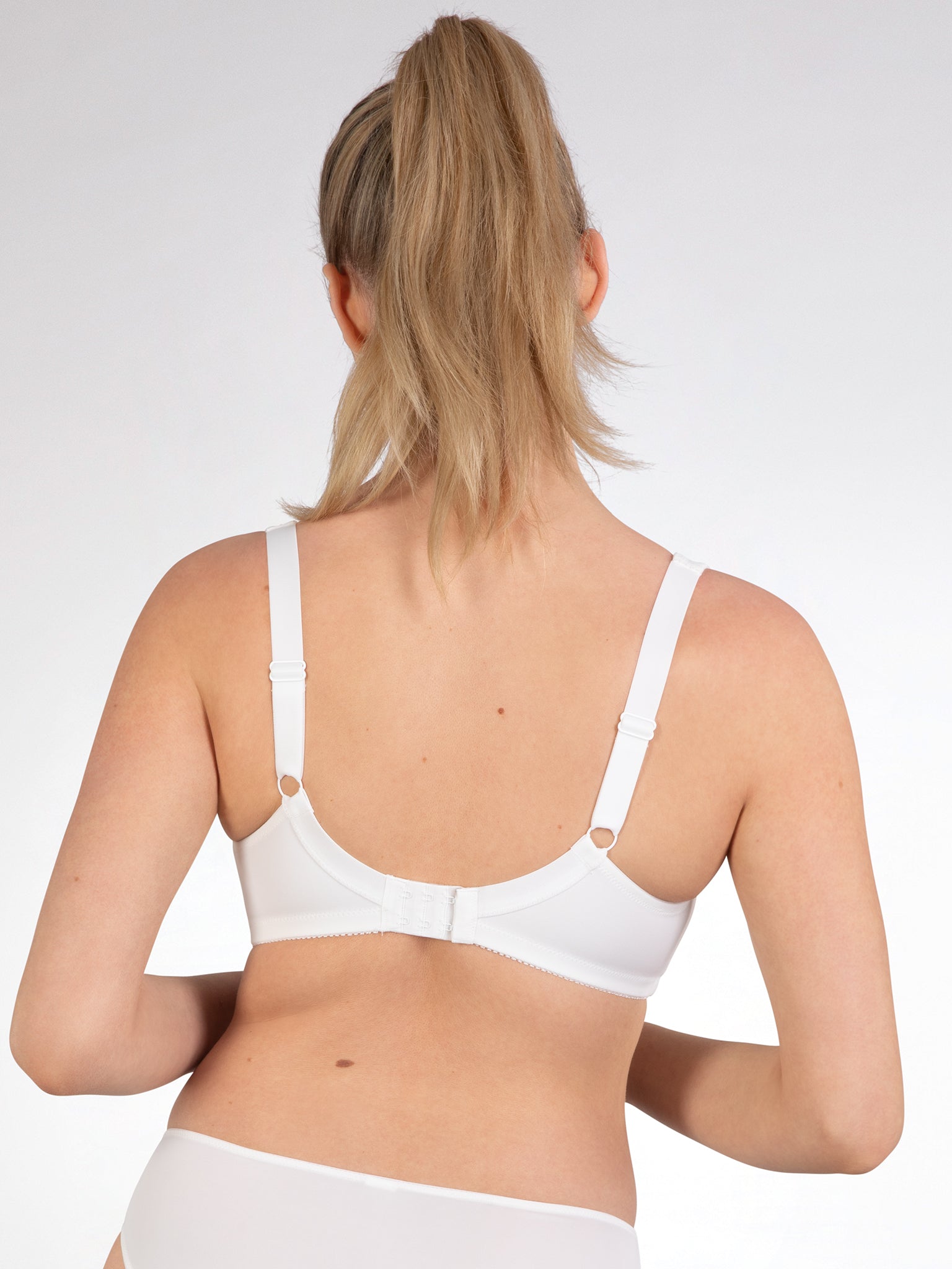 Achterzijde van vrouw die de prothese bh in de kleur ecru van het merk Naturana draagt