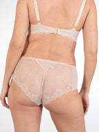 Achterzijde van vrouw die de slip met kant in de kleur beige van het merk Naturana draagt