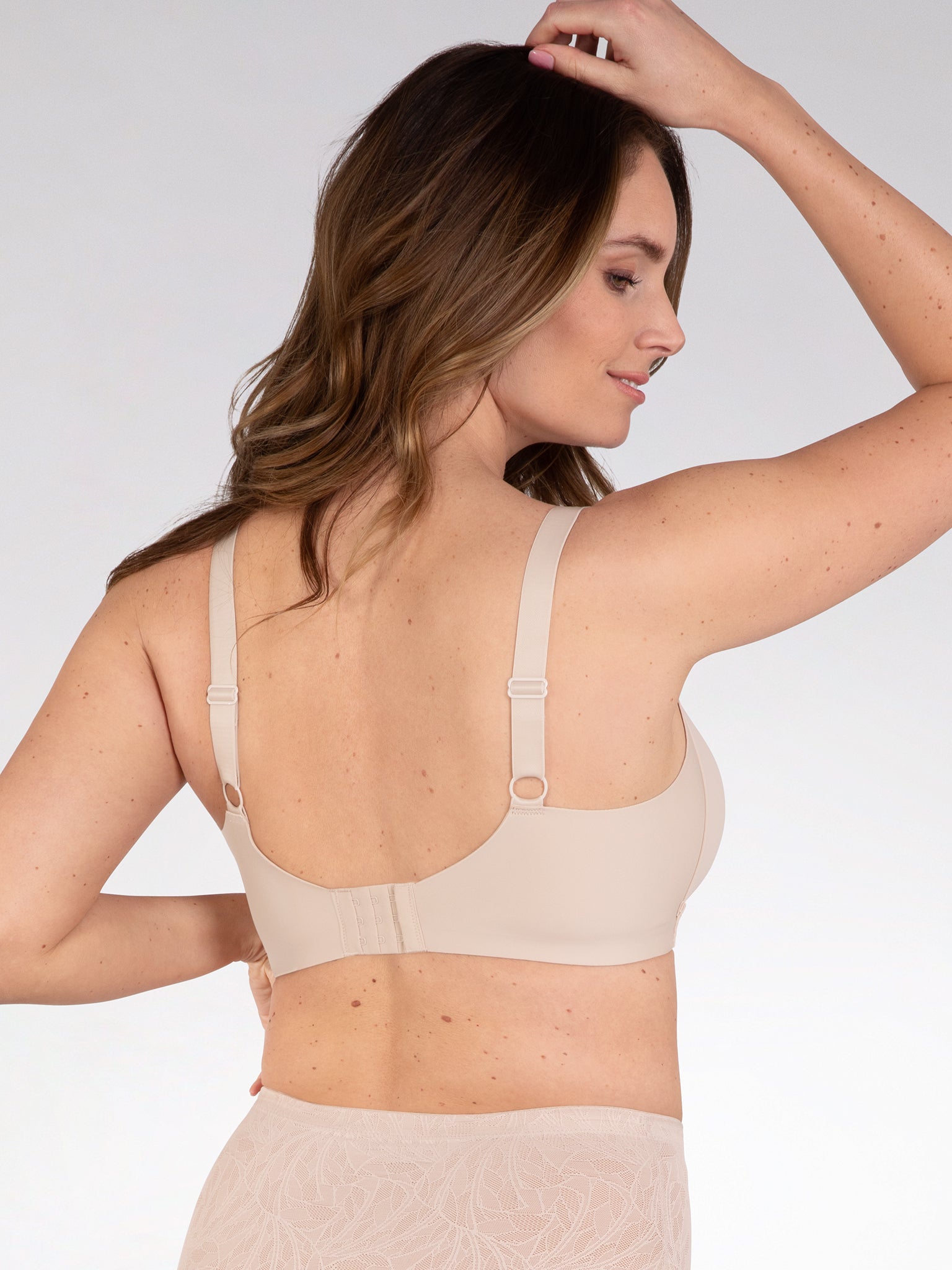 Achterzijde van vrouw die de side smoother bh zonder beugel in de kleur beige van het merk Naturana draagt