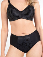 Voorzijde van vrouw die de minimizer bh met bloemenpatroon en slip met bloemenpatroon in de kleur zwart van het merk Naturana draagt