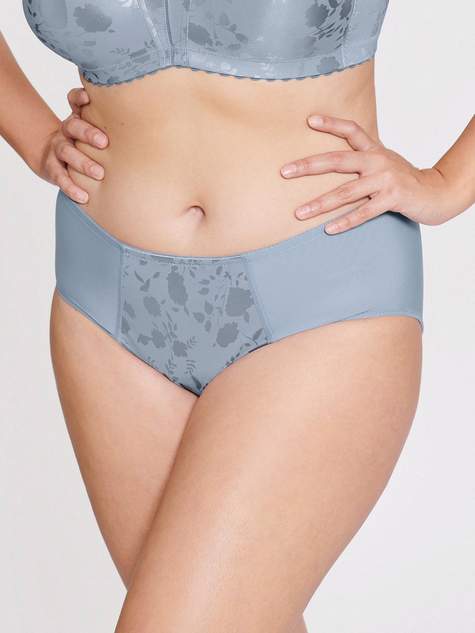Voorzijde van vrouw die de minimizer slip met bloemenpatroon in de kleur raindrops van het merk Naturana draagt