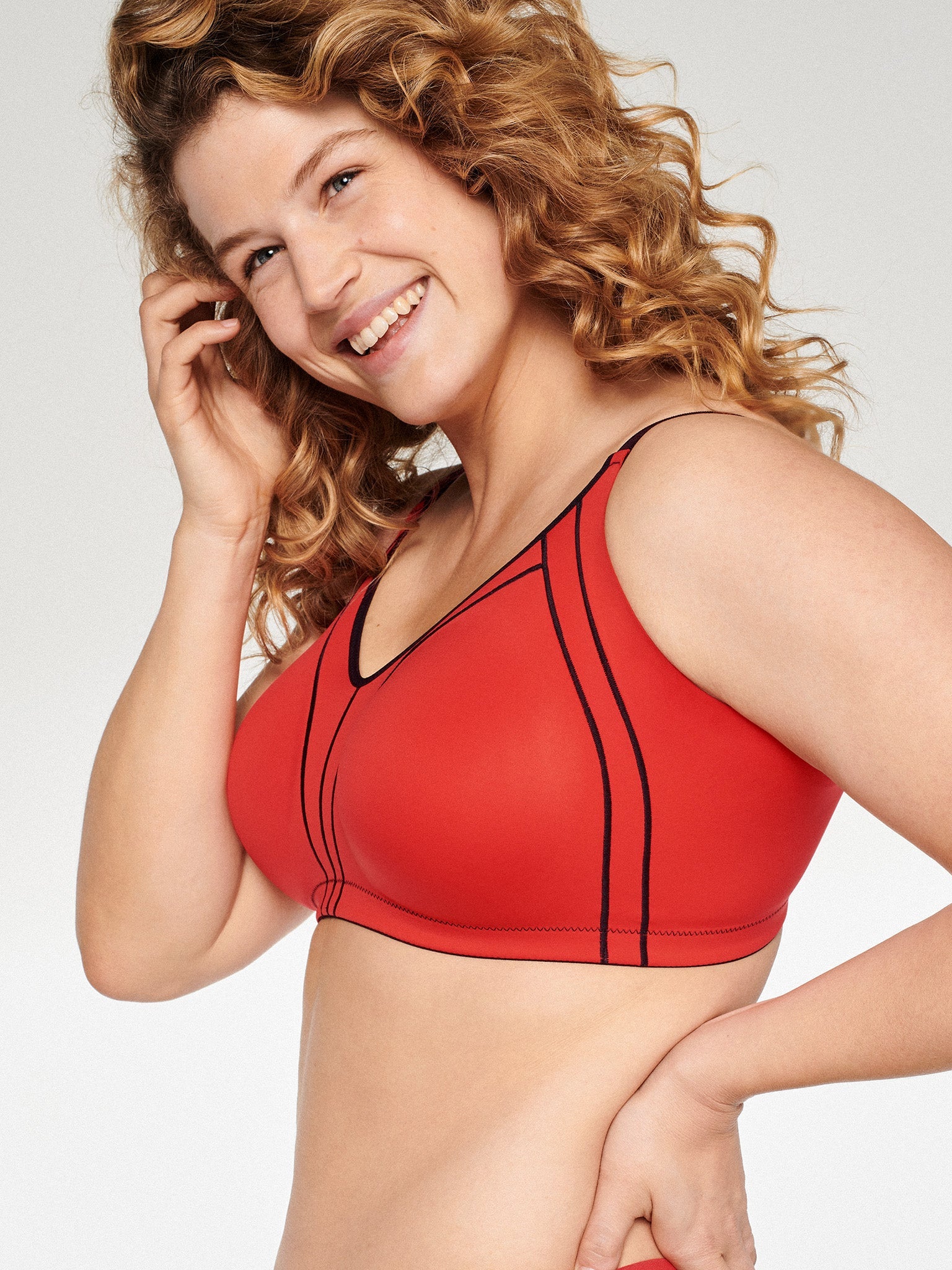 Zijde van vrouw die de minimizer bh met side smoother in de kleur rood van het merk Naturana draagt