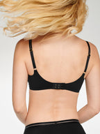 Achterzijde van vrouw die de soft bh met mesh detail en de slip met mesh detail in de kleur zwart van het merk Naturana draagt