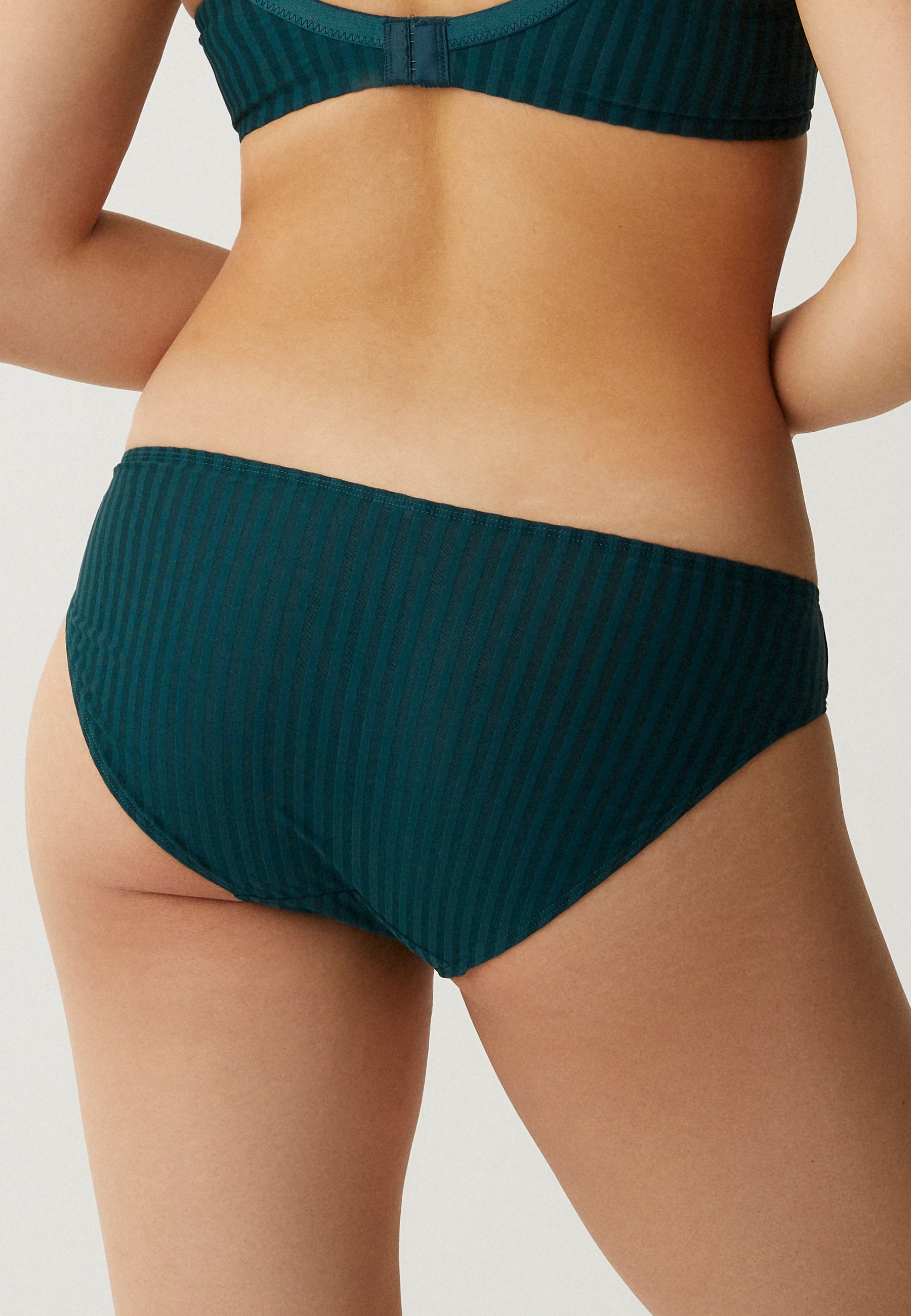 Achterzijde van vrouw die de slip met strepen in de kleur groen van het merk Naturana draagt