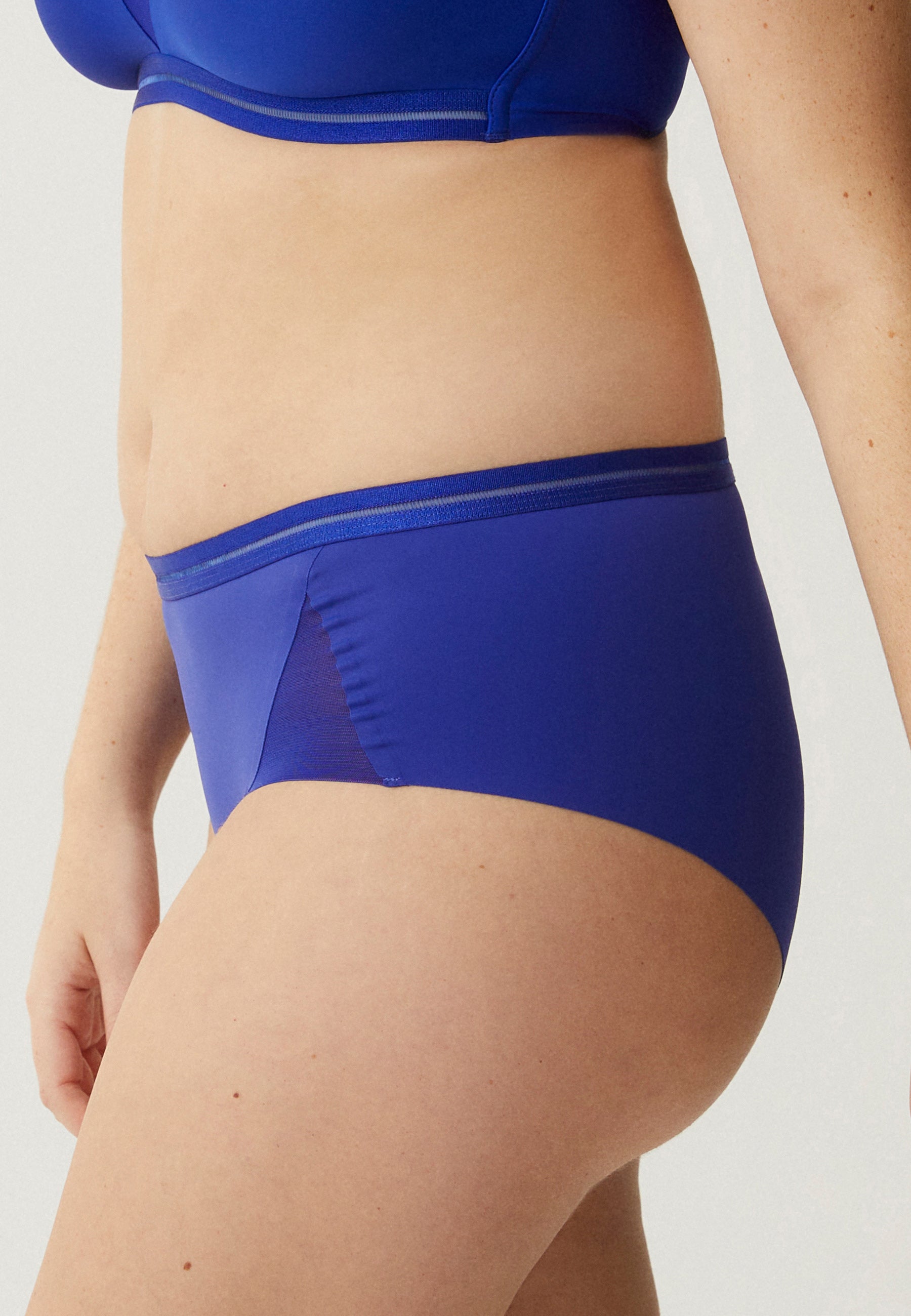 Zijde van vrouw die de slip met mesh detail in de kleur indigo  van het merk Naturana draagt