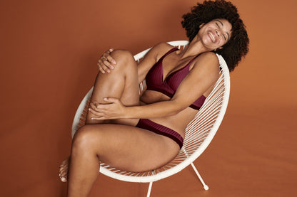 Zijde van vrouw die de soft bh met strepen en slip met strepen in de kleur burgundy van het merk Naturana draagt
