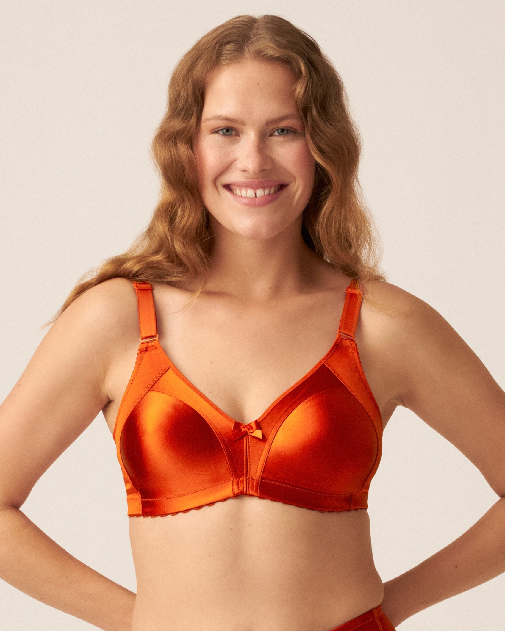 Voorzijde van vrouw die de minimizer bh met glanzend patroon in de kleur orange saffron van het merk Naturana draagt