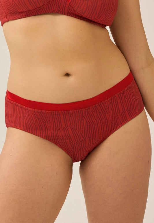 Voorzijde van vrouw die de soft bh met glansband en slip met glansband in de kleur negroni print van het merk Naturana draagt