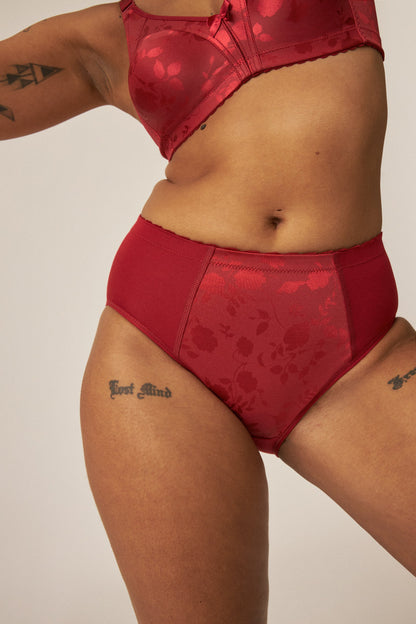 Voorzijde van vrouw die de minimizer bh met bloemenpatroon en minimizer slip met bloemenpatroon in de kleur Deep Claret van het merk Naturana draagt