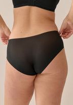 Achterzijde van vrouw die de slip one size in de kleur zwart van het merk Naturana draagt
