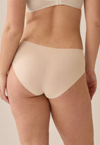 Achterzijde van vrouw die de slip one size in de kleur beige van het merk Naturana draagt