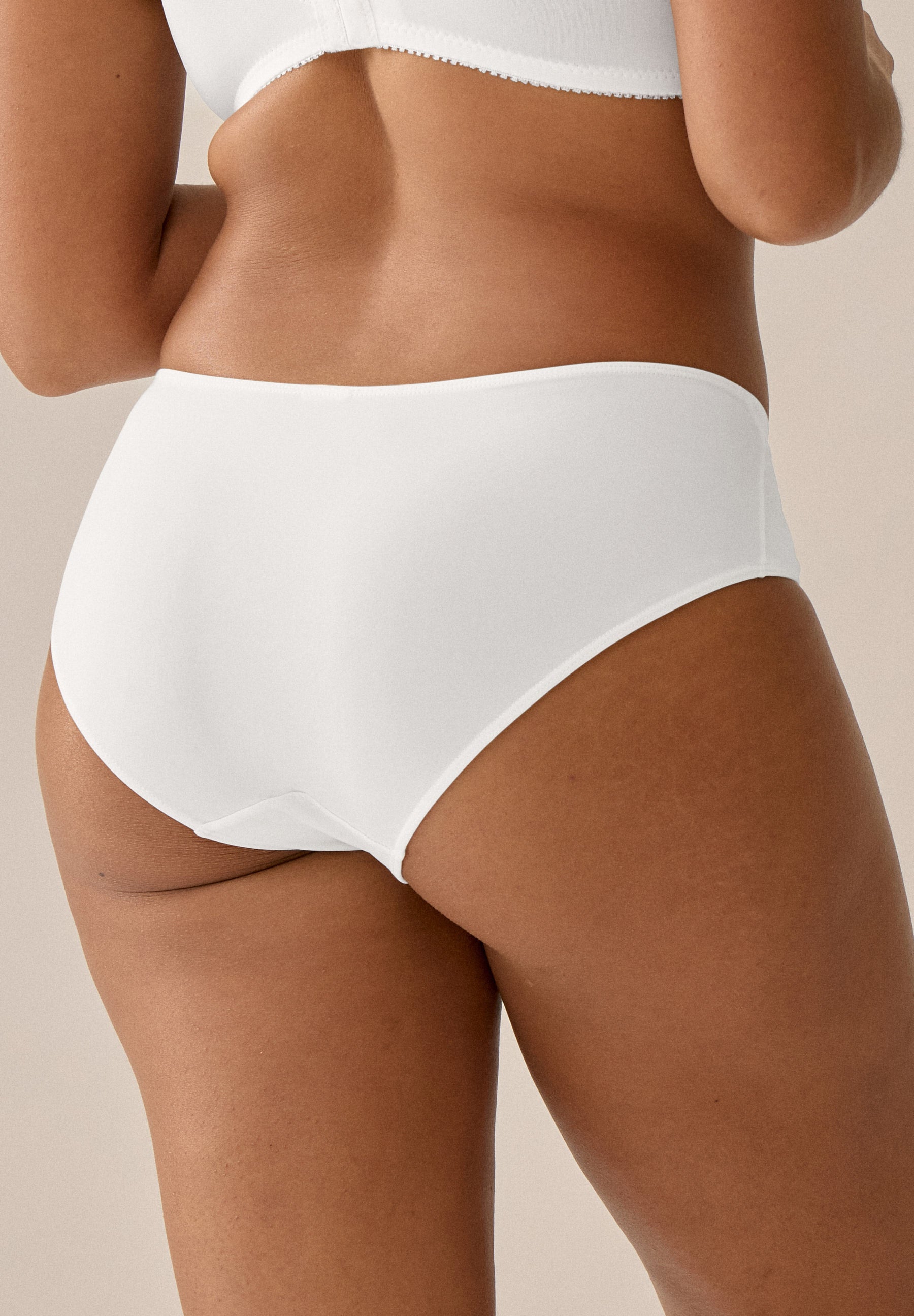 Achterzijde van vrouw die de slip met glansband in de kleur ecru van het merk Naturana draagt