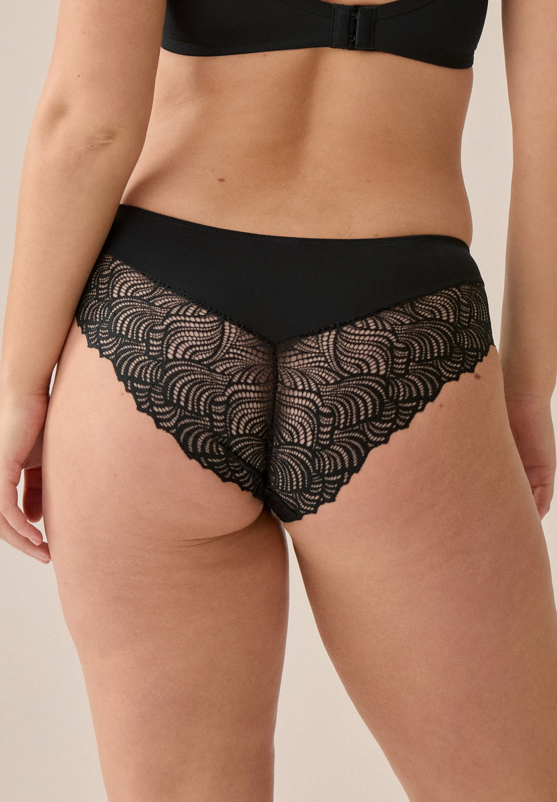 Achterzijde van vrouw die de hipster met kant in de kleur zwart van het merk Naturana draagt