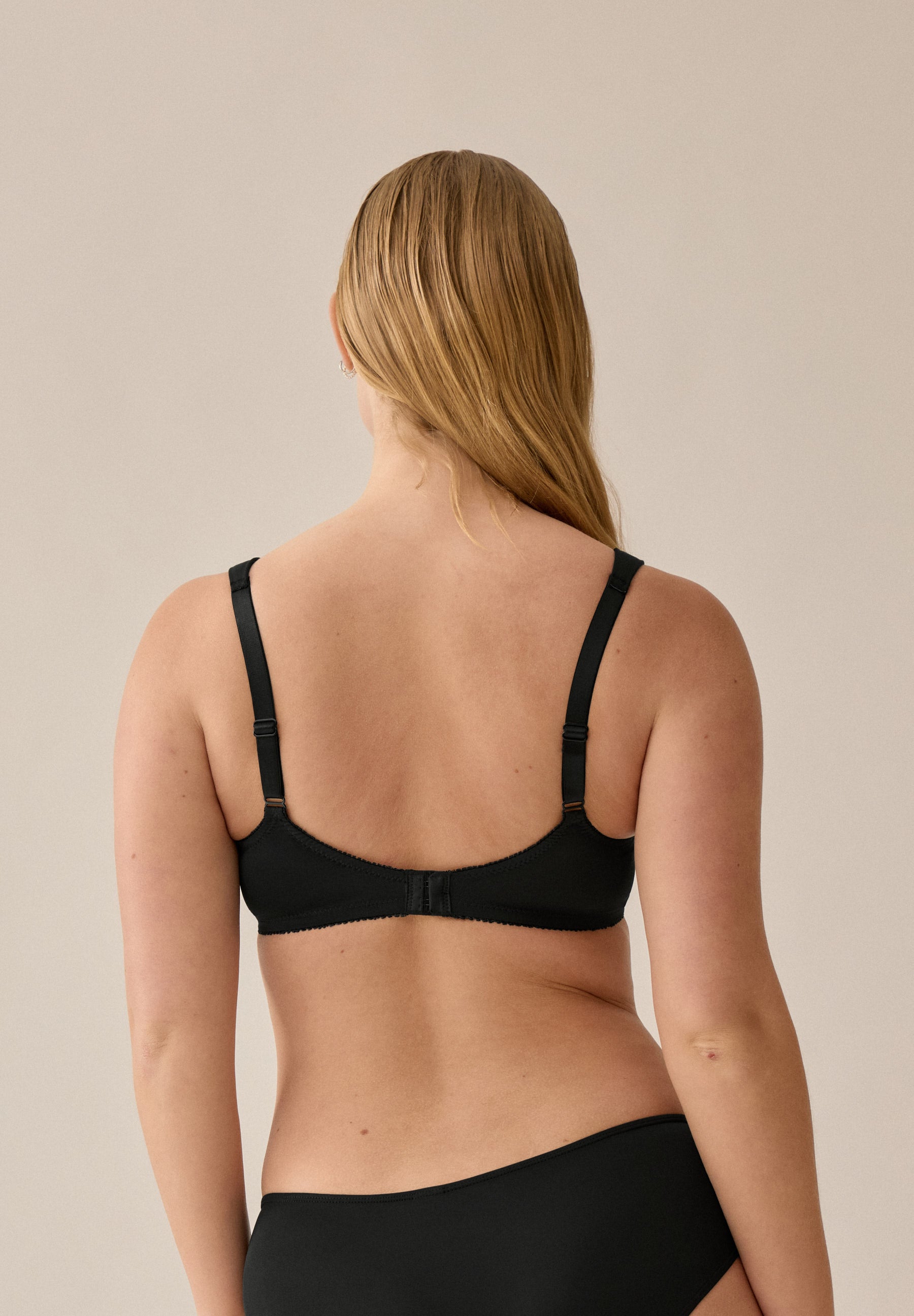 Achterzijde van vrouw die de soft bh met brede bandjes in de kleur zwart van het merk Naturana draagt