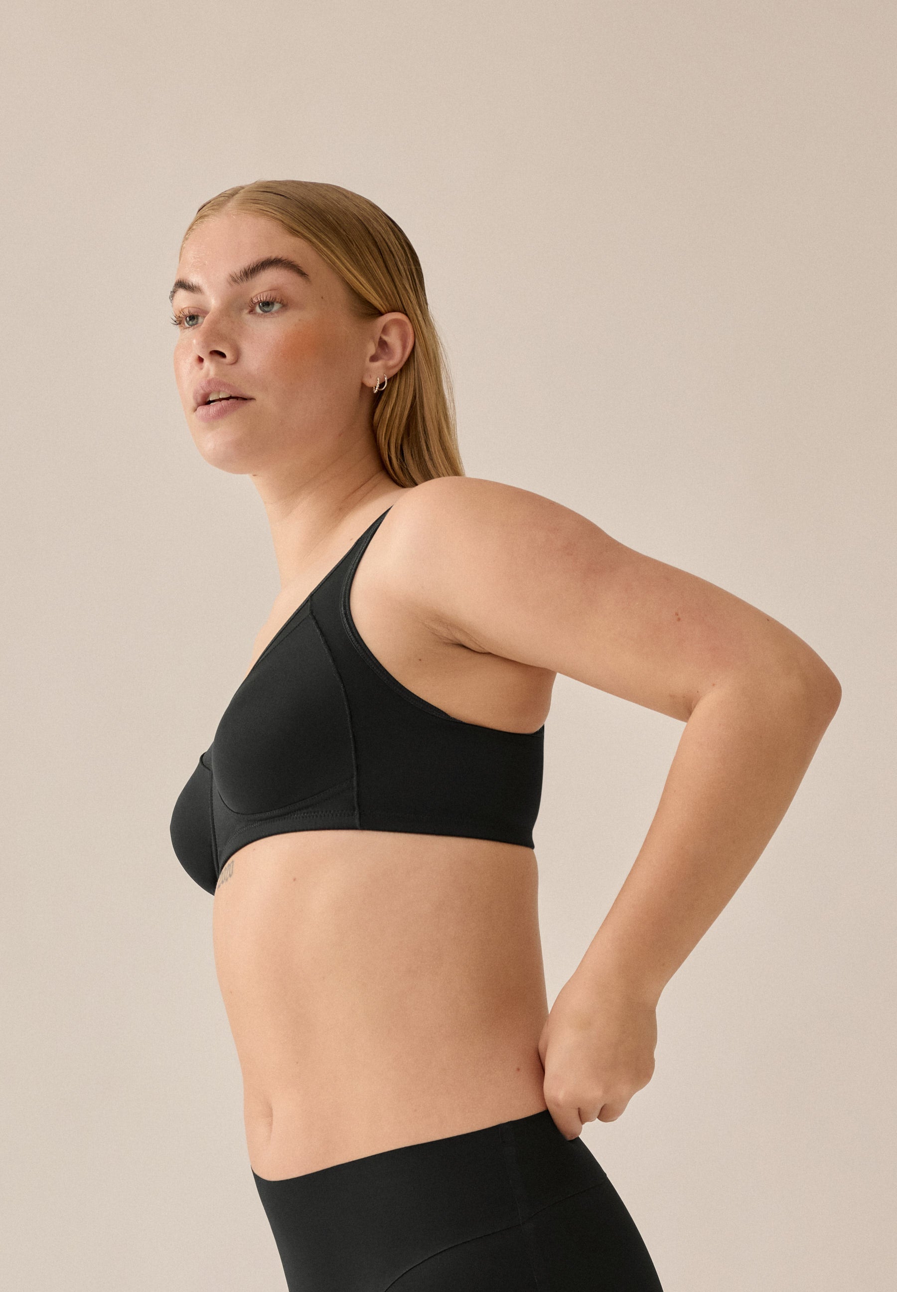 Zijde van vrouw die de soft bh met meshrand in de kleur zwart van het merk Naturana draagt