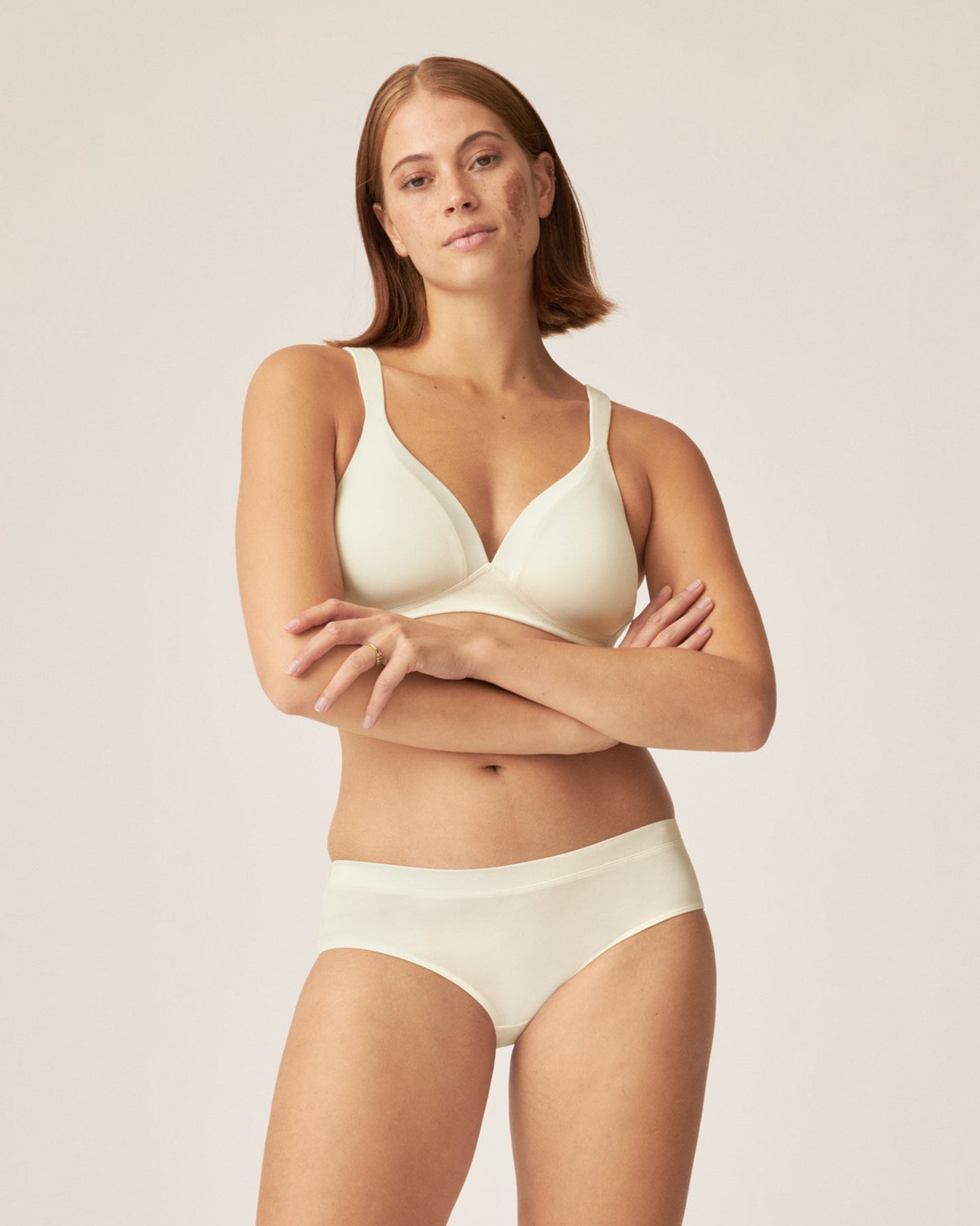 Voorzijde van vrouw die de soft bh met glansband en slip met glansband in de kleur ecru van het merk Naturana draagt