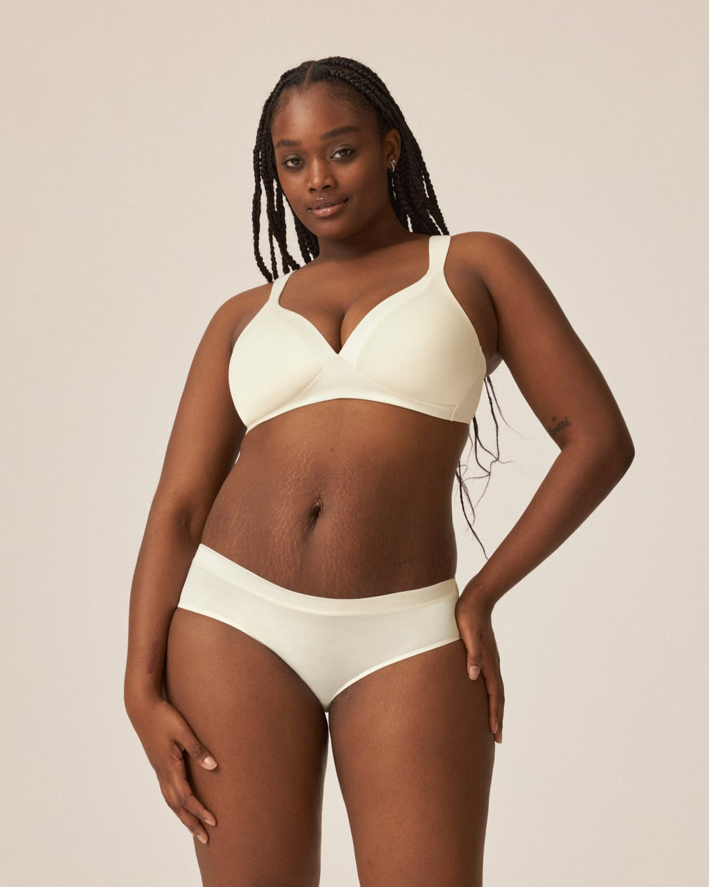 Voorzijde van vrouw die de soft bh met glansband en slip met glansband in de kleur ecru van het merk Naturana draagt