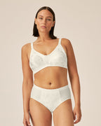 Voorzijde van vrouw die de minimizer bh met bloemenpatroon en slip met bloemenpatroon in de kleur Ivoor van het merk Naturana draagt