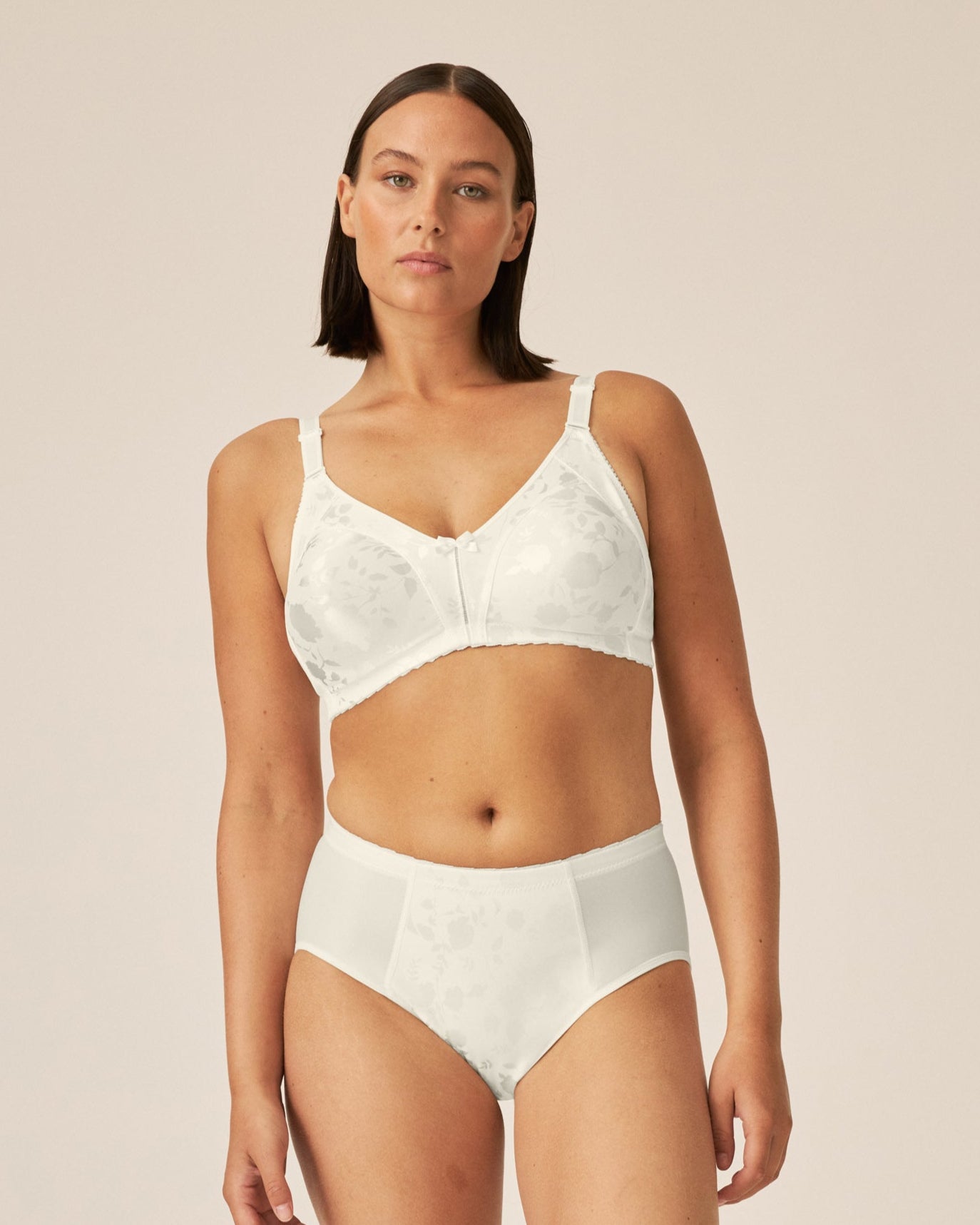 Voorzijde van vrouw die de minimizer bh met bloemenpatroon en slip met bloemenpatroon in de kleur Ivoor van het merk Naturana draagt
