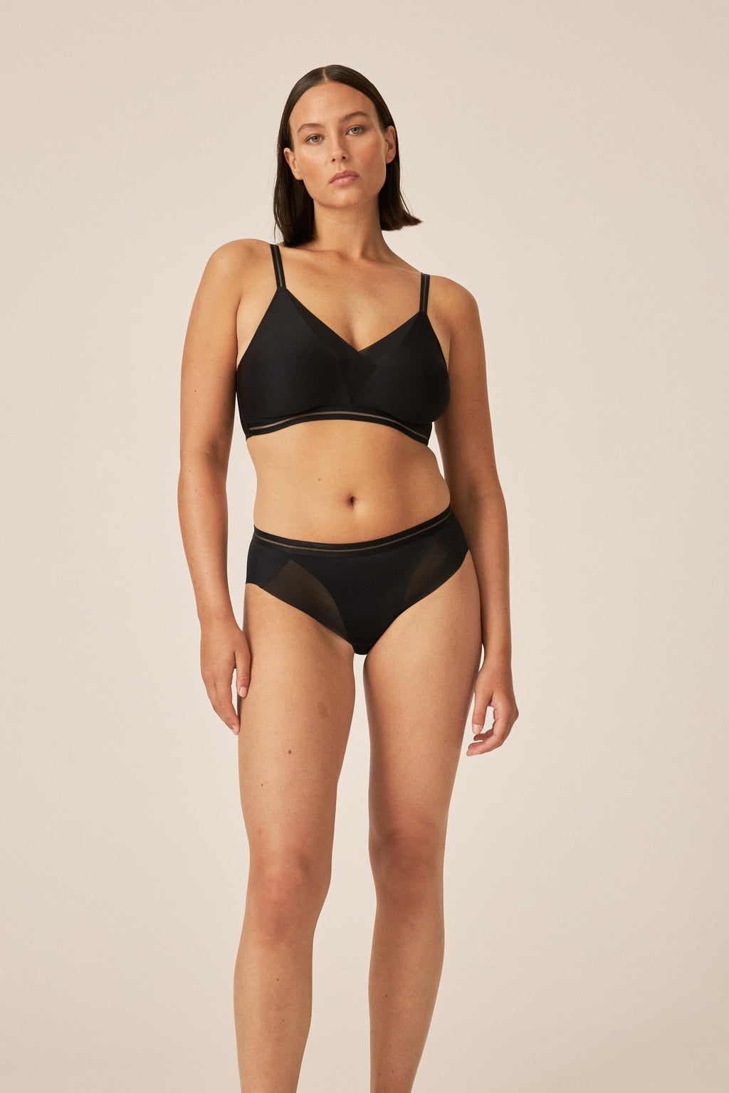 Voorzijde van vrouw die de soft bh met mesh detail en slip met mesh detail in de kleur zwart van het merk Naturana draagt