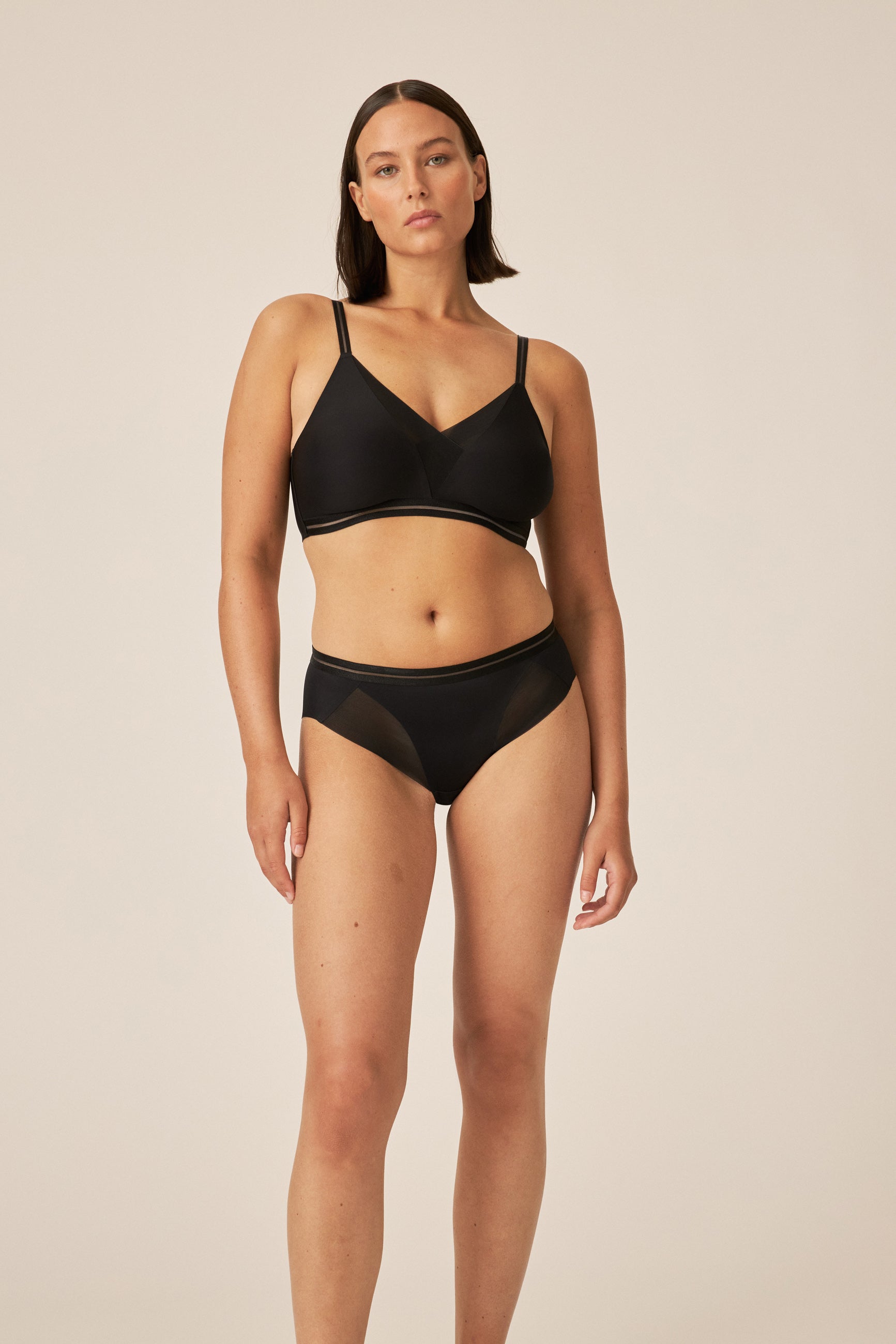 Voorzijde van vrouw die de soft bh met mesh detail en slip met mesh detail in de kleur zwart van het merk Naturana draagt