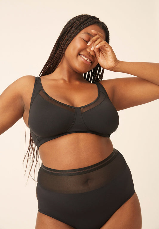 Voorzijde van vrouw die de soft bh met meshrand en hoge slip met mesh detail in de kleur zwart van het merk Naturana draagt