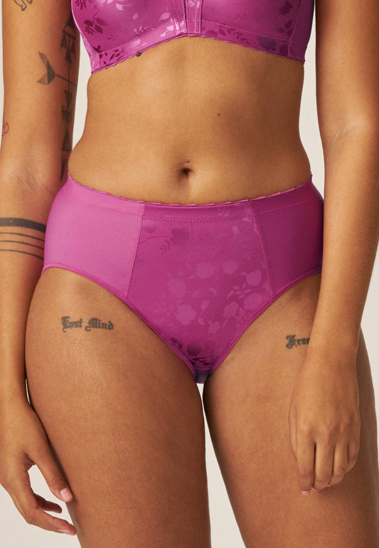 Voorzijde van vrouw die de minimizer slip met bloemenpatroon in de kleur Purple Orchid van het merk Naturana draagt