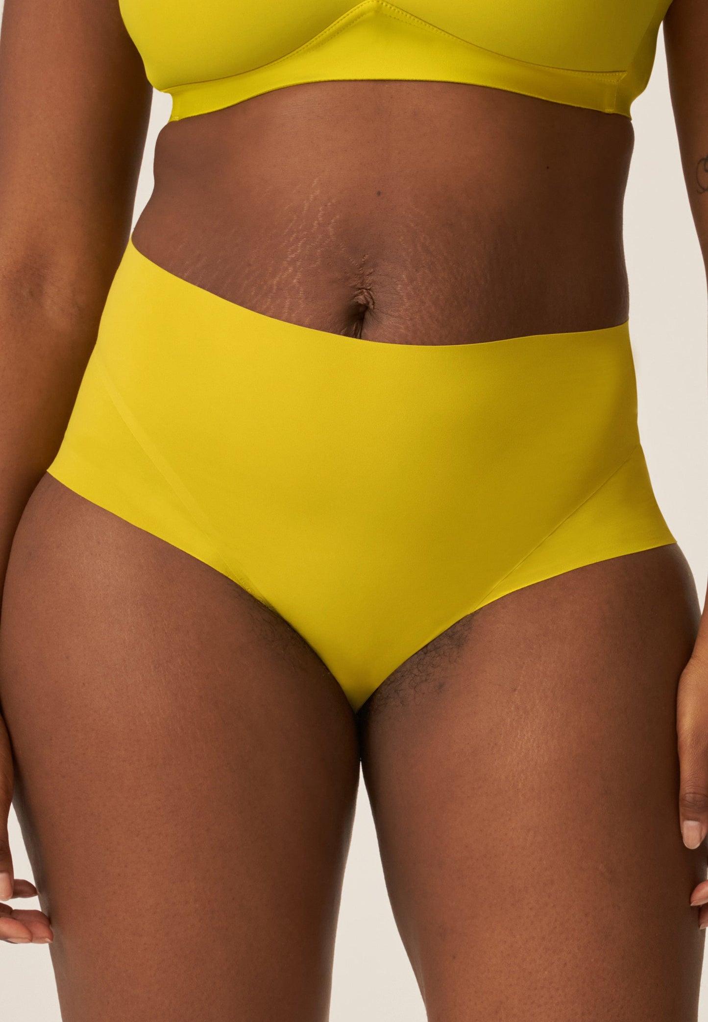 Voorzijde van vrouw die de side smoother bh en high waist slip in de kleur golden olive van het merk Naturana draagt
