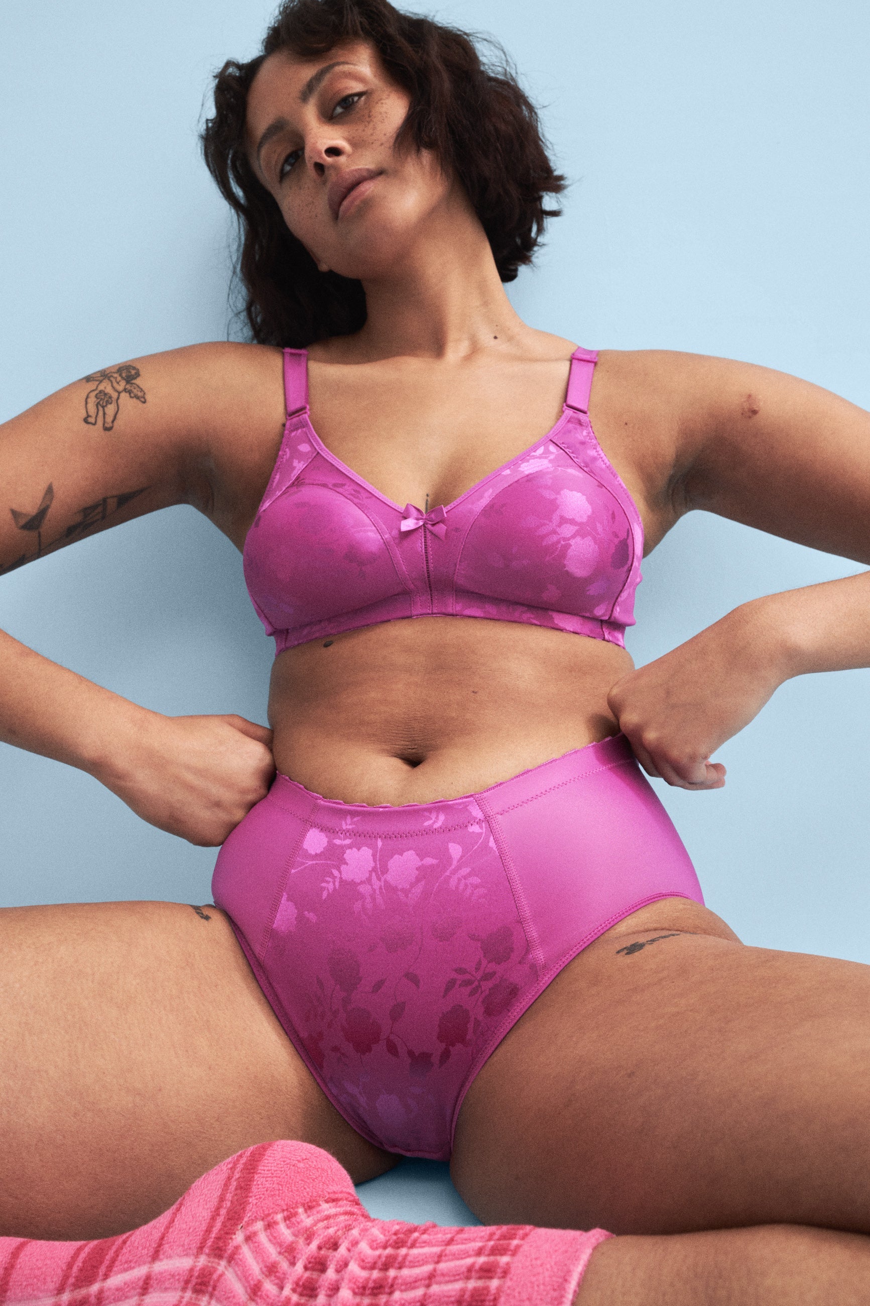 Voorzijde van vrouw die de minimizer bh met bloemenpatroon en minimizer slip met bloemenpatroon in de kleur Purple Orchid van het merk Naturana draagt