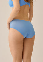 Achterzijde van vrouw die de one size slip in de kleur marina blue van het merk Naturana draagt