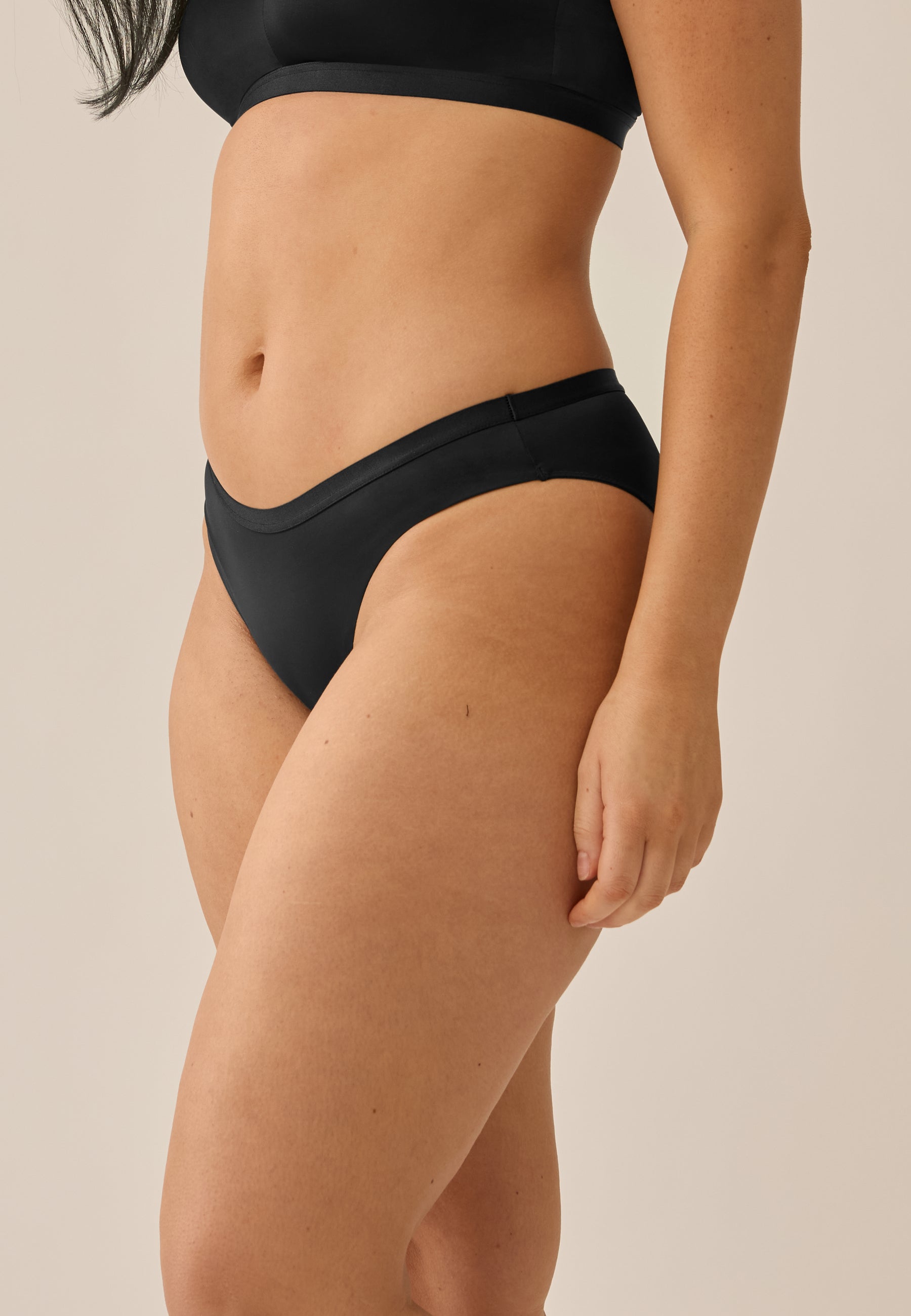 Zijde van vrouw die de string in de kleur zwart van het merk Naturana draagt