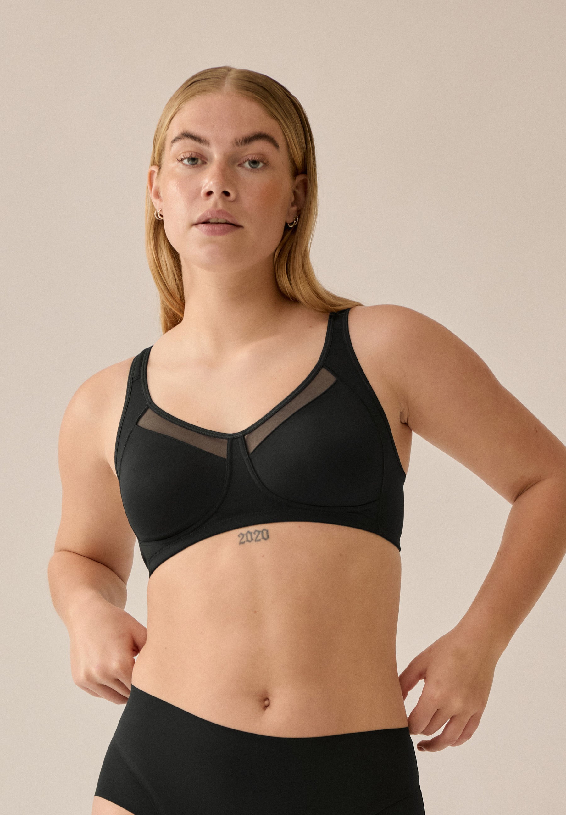 Voorzijde van vrouw die de soft bh met meshrand in de kleur zwart van het merk Naturana draagt