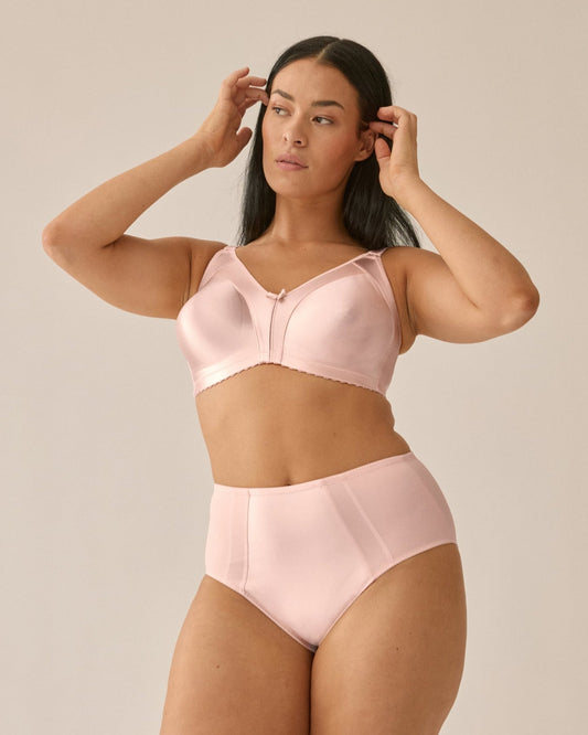 Voorzijde van vrouw die de minimizer bh met glanzend patroon en slip met glanzend patroon in de kleur blush van het merk Naturana draagt