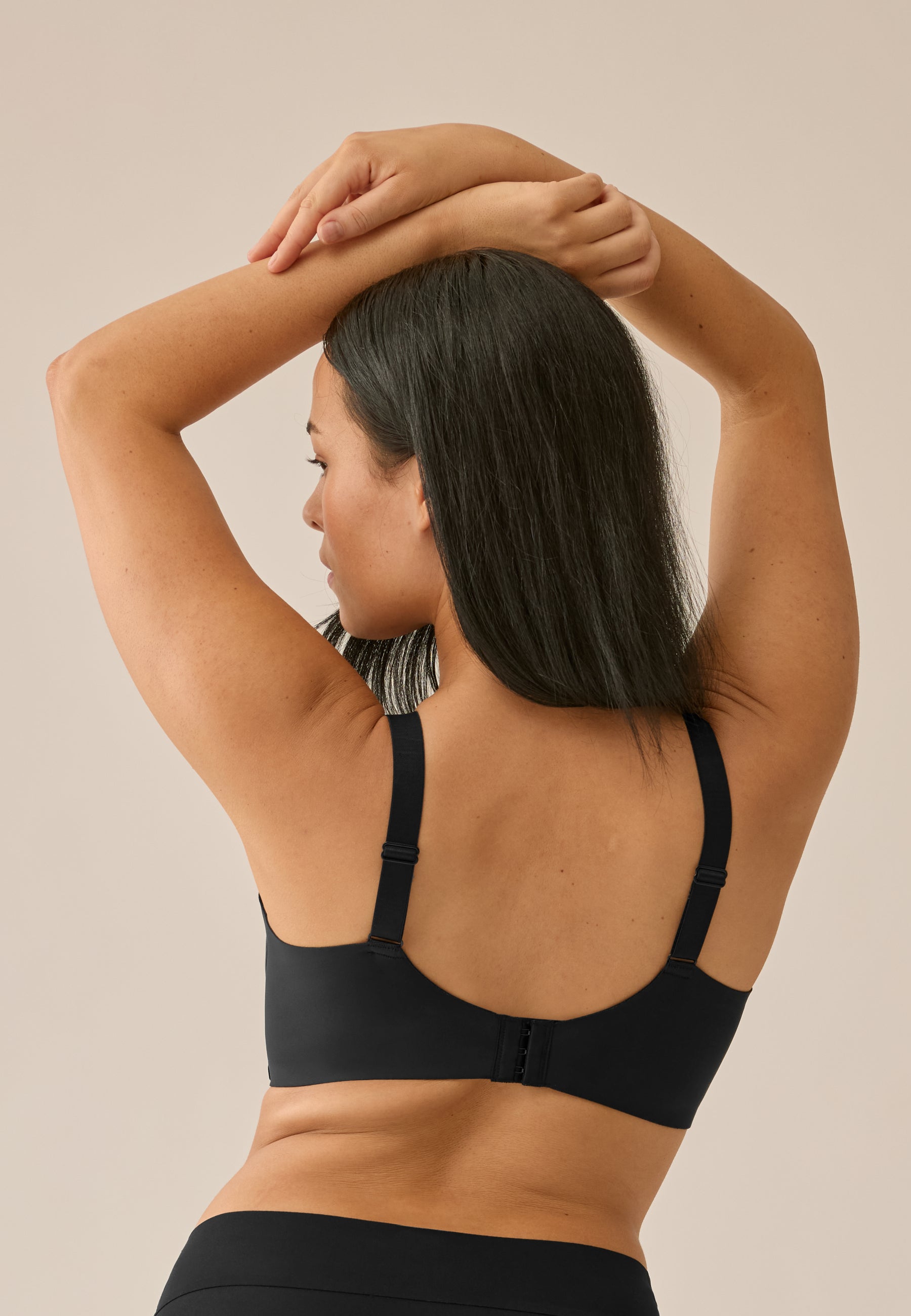 Achterzijde van vrouw die de side smoother bh in de kleur zwart van het merk Naturana draagt