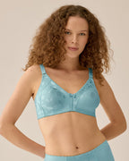 Voorzijde van vrouw die de minimizer bh met bloemenpatroon en slip met bloemenpatroon in de kleur Aquamarine van het merk Naturana draagt