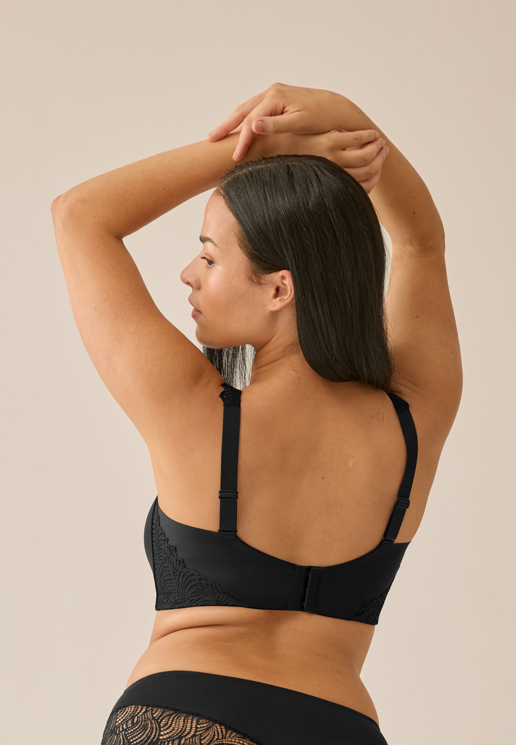 Achterzijde van vrouw die de side smoother bh met kant in de kleur zwart van het merk Naturana draagt