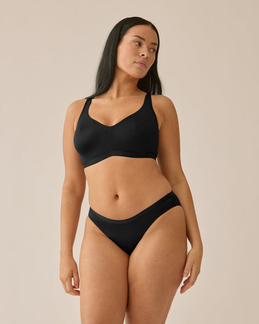 Voorzijde van vrouw die de minimizer bh en slip in de kleur zwart van het merk Naturana draagt